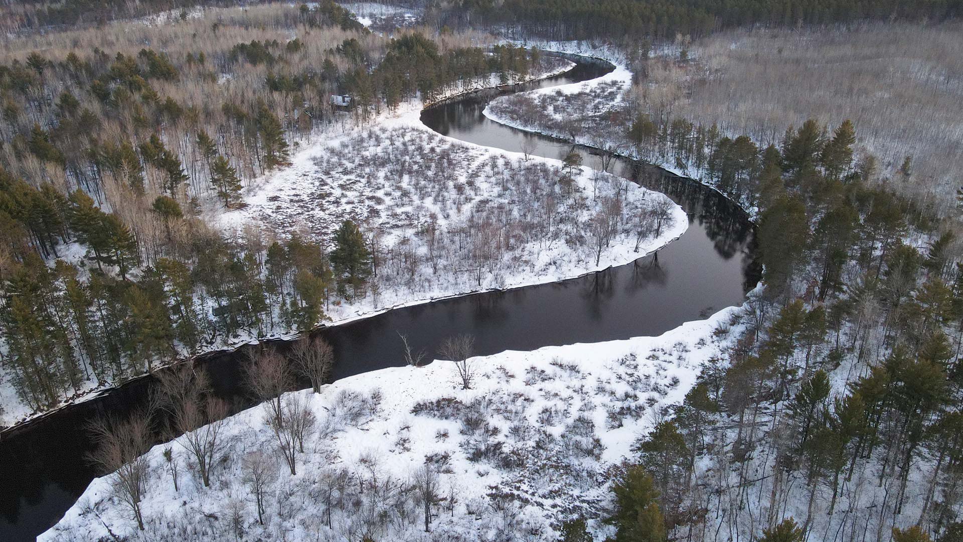 Drone photo of river surrounded by snow